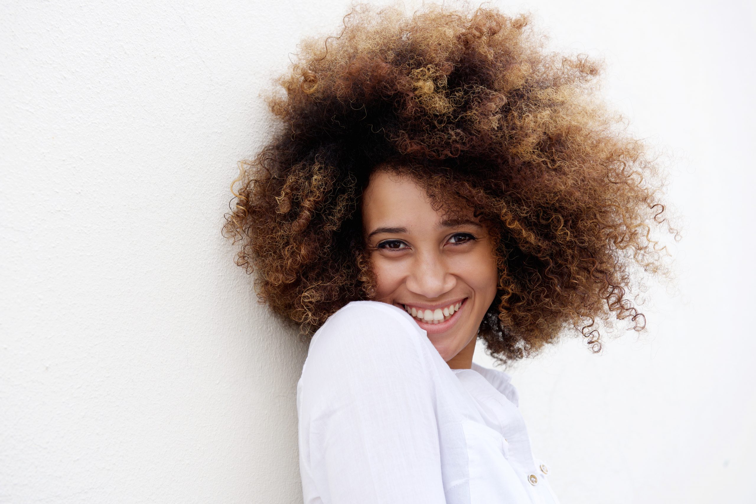 Young woman smiling with afro hair against white background